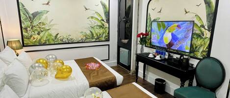Ein Hotelzimmer mit einem Bett, einem Schreibtisch mit Computer, einem Stuhl und einem Fernseher.