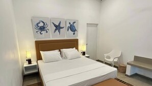 Un dormitorio moderno con una cama grande, cabecera de madera y ventilador de techo. Hay dos lámparas de pared y una mesita de noche.