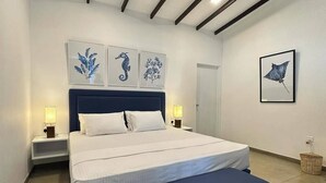 Un dormitorio moderno con una cama grande, mesitas de noche y obras de arte en las paredes.