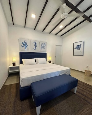 Quarto moderno com uma cama grande, mesas de cabeceira e obras de arte nas paredes.