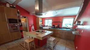 A kitchen with a central island, wooden cabinets, a built-in oven, and a window providing natural light. - Beautiful modern villa with swimming pool in the heart of the garrigue (Lauret)