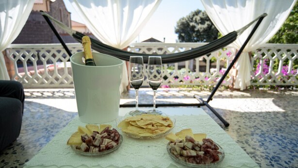 Une table dressée avec une bouteille de champagne, deux verres et trois bols remplis de nourriture.