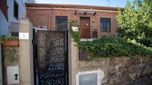Un immeuble résidentiel avec une façade en briques, un portail en métal orné de motifs décoratifs et un petit balcon.