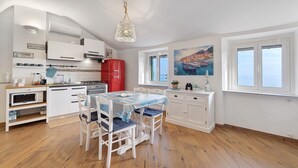 A modern kitchen with white cabinets, a red refrigerator, and a dining table with chairs. - Apartment 'Bedliving Nel Blu' with Sea View, Wi-Fi and Air Conditioning (Genova)