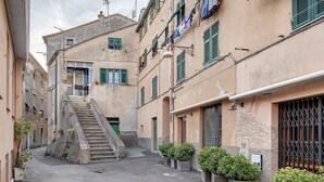A narrow alleyway with buildings on either side, a staircase, and potted plants. - Apartment 'Bedliving Nel Blu' with Sea View, Wi-Fi and Air Conditioning (Genova)