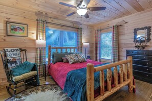 A cozy cabin bedroom with a wooden bed, a rocking chair, and a dresser.