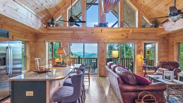 Een ruime cabin met keuken, eethoek en een gezellige woonkamer met open haard. Grote ramen bieden uitzicht op het omliggende landschap.