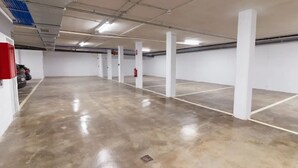 Ruime parkeerplaats binnenshuis, met betonnen vloeren en witte zuilen.