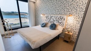 Een slaapkamer met een groot bed, uitzicht op het strand en behang met een patroon.