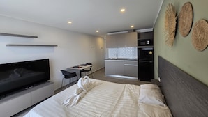 Una camera d'albergo moderna con un letto, una TV, angolo cottura e zona pranzo.