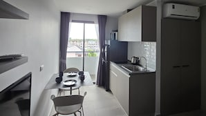 Una cucina compatta con zona pranzo, forno a microonde integrato, bollitore e vista dalla finestra.
