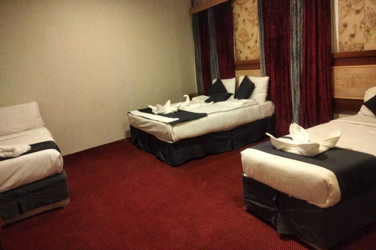 A hotel room with two beds, a red carpet, and a wooden headboard.