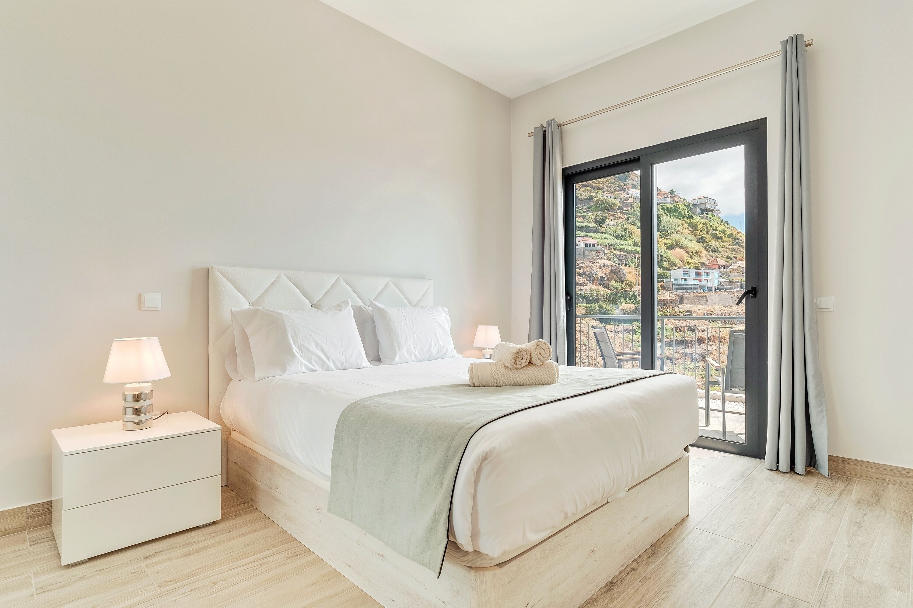 Une chambre à coucher avec un lit, des tables de chevet et une vue sur une colline.
