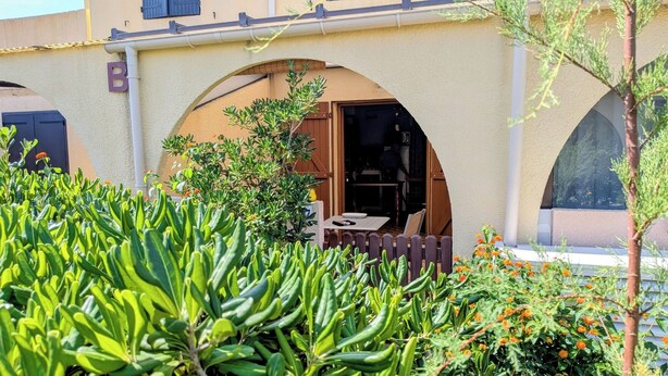 A building with a beige facade, a wooden fence, and a table with chairs outside. - Ground-floor Studio Cabin with terrace. Pets welcome! (leucate)