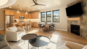 A modern kitchen with a dining area, a fireplace, and a TV mounted on the wall.