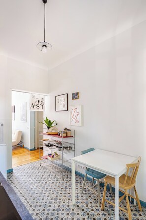 A modern kitchen with a white table, blue chairs, and a patterned floor.