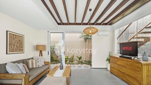 A modern living room with a sofa, coffee table, and TV stand. - Ombak Villa by Kozystay - Canggu (Canggu)