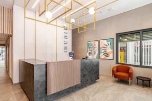 Un comptoir d’accueil au design moderne, une chaise et des œuvres d’art accrochées au mur.