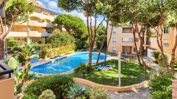 A residential building with a swimming pool surrounded by lush greenery and trees. - Beach and Golf Design Apartment Marbella (Marbella)