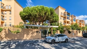 A residential building with a covered entrance, a car parked in front, and a tree in the center. - Beach and Golf Design Apartment Marbella (Marbella)