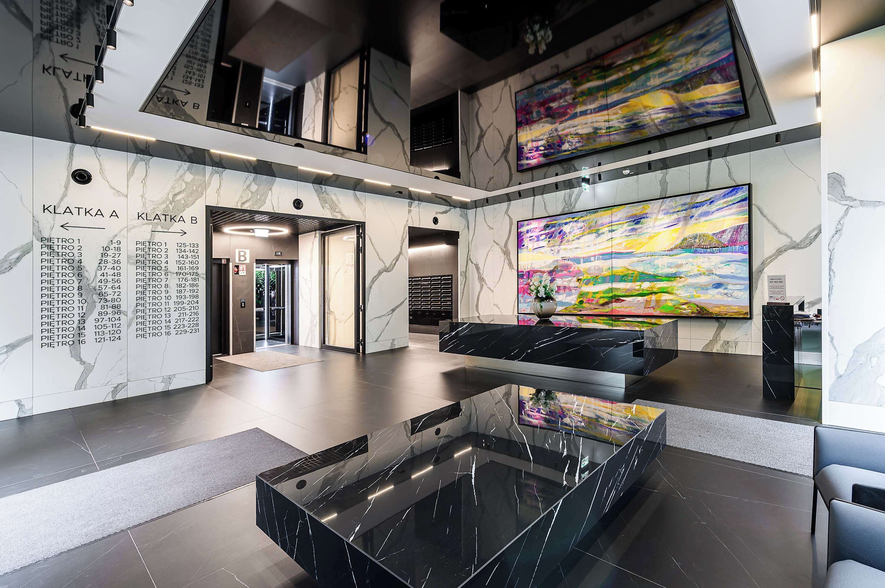 A modern lobby with a marble floor, a glass coffee table, and a large abstract painting.