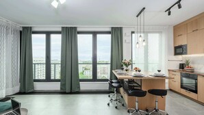 A modern apartment with a kitchen, dining area, and a large window with a city view. - 2-Room Apart on 15th Floor (Warszawa)