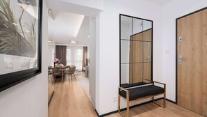 Ein modernes Hotelzimmer mit Holzboden, einem großen Spiegel, einer Bank und einer Tür.