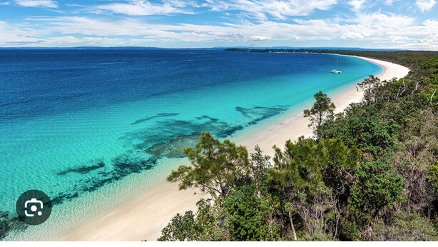A beach with clear turquoise waters, a sandy shore, and dense greenery. - 3 minute drive to the beach! Family home with a BBQ, boardgames, and a backyard. (Callala Bay)