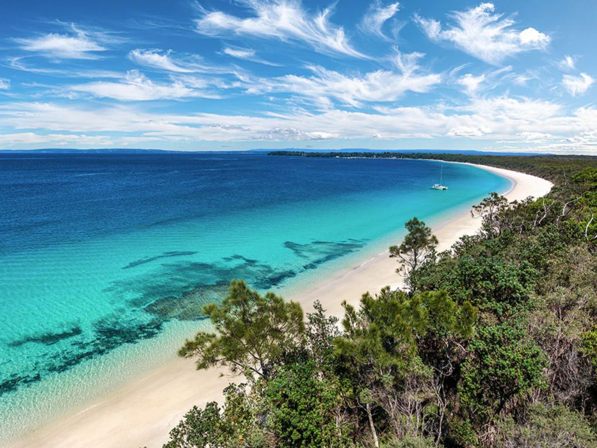 Una spiaggia con acque cristalline turchesi, una riva sabbiosa e una vegetazione lussureggiante.