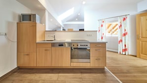 Een moderne keuken met houten kastjes, een inbouwoven en een magnetron.