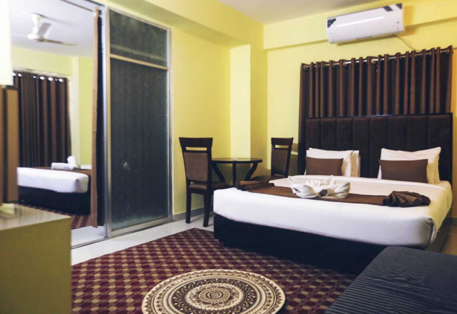 Habitación de hotel con una cama, una silla, una mesa y un ventanal corredero.