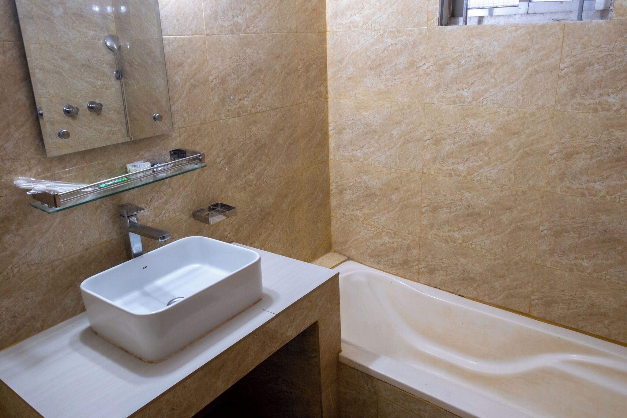 Une salle de bain avec un lavabo blanc, une étagère en verre, un miroir et une baignoire.