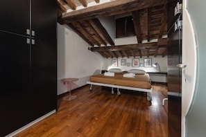 Ein Schlafzimmer mit Bett, Holzbalken, Schreibtisch und Kleiderschrank.