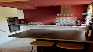 A modern kitchen with a central island, bar stools, and a microwave.