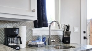 Una cocina con cafetera, un lavabo y un bloque de cuchillos.