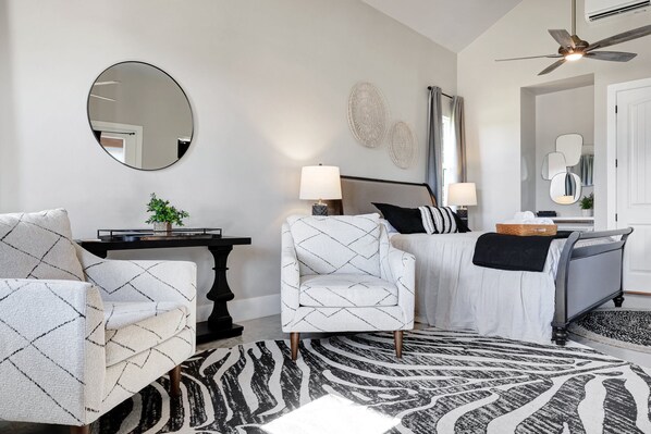 A modern living room with a sofa, armchair, and a round mirror on the wall.