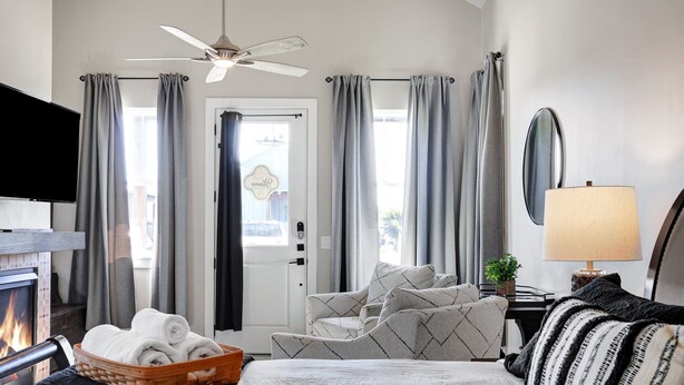 Habitación de hotel con cama, televisión, chimenea, ventilador de techo y vistas al exterior.