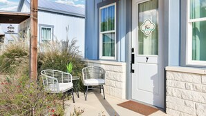 A house with a white door marked with the number 7, a porch with two white chairs, and a wooden pergola. - Frio - A Birdy Vacation Rental (Fredericksburg)