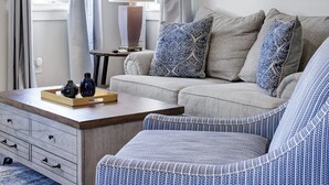 A room with a sofa, a chair, a lamp, a mirror, and a window with curtains. - Frio - A Birdy Vacation Rental (Fredericksburg)