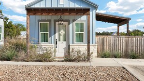 A small, single-story building with a blue exterior and a wooden porch. - Frio - A Birdy Vacation Rental (Fredericksburg)