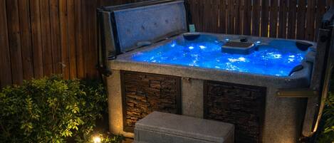 A hot tub with a stone exterior and a wooden fence in the background.