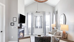 A modern living room with a fireplace, a sofa, a coffee table, and a television.