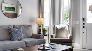 Ein modernes Wohnzimmer mit einem grauen Sofa, einem Couchtisch, einer Lampe und einem Sessel.