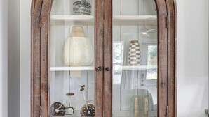 A wooden cabinet with glass doors, featuring a bottle and decorative items inside.