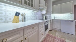 A kitchen with white cabinets, a stainless steel range hood, a dishwasher, and a tiled backsplash. - Ferienwohnung Salzafeld (Bad Mitterndorf)