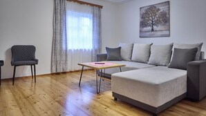 A living room with a grey sofa, a small armchair, and a wooden floor. - Ferienwohnung Salzafeld (Bad Mitterndorf)