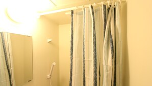 Une salle de bain avec un rideau de douche, un miroir et une douchette à main.