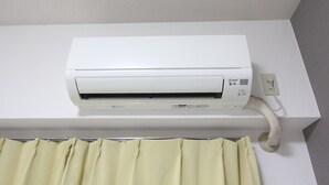 Un appareil de climatisation blanc, fixé au mur, avec un panneau de commande et un câble d’alimentation.