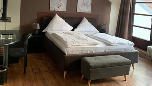 A bedroom with a bed, bedside tables, a desk, and a window.