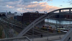 A cityscape with a prominent bridge, railway tracks, and a river.